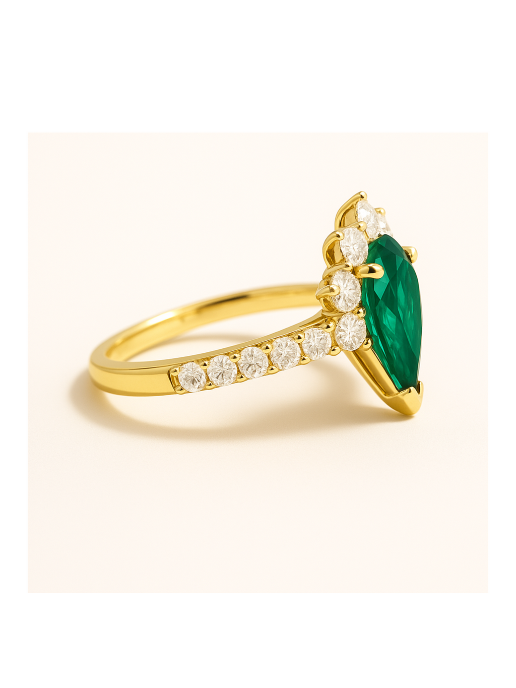 Emerald Diamond Gold Ring - Queens Crown features a pear-cut emerald centerpiece with round diamonds on a gold band. Luxury gold jewelry for elegant style.